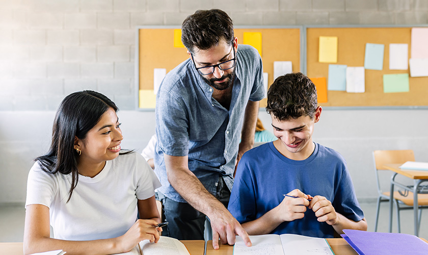 Profesor leyendo un cuaderno a sus alumnos en el salón de clases