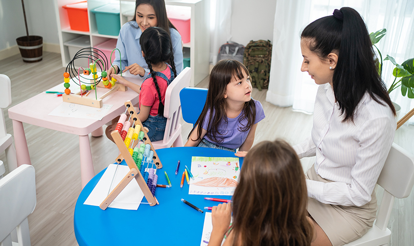 Profesora de inicial enseñándole a pintar a sus alumnos
