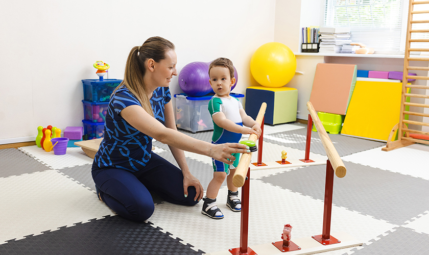 Profesora enseñando a caminar a niño con ejercicios de psicomotricidad