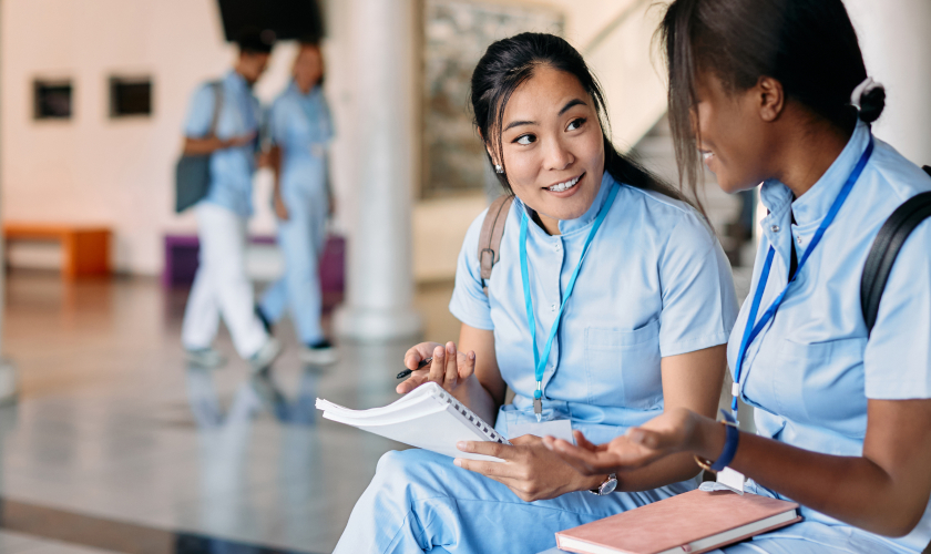 Dos alumnas de Enfermería conversando sentadas en una banca