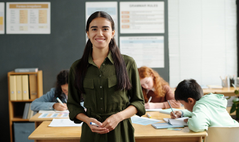 Joven profesora frente a sus alumnos que están escribiendo en sus cuadernos