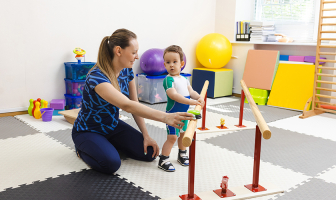 Profesora enseñando a caminar a niño con ejercicios de psicomotricidad
